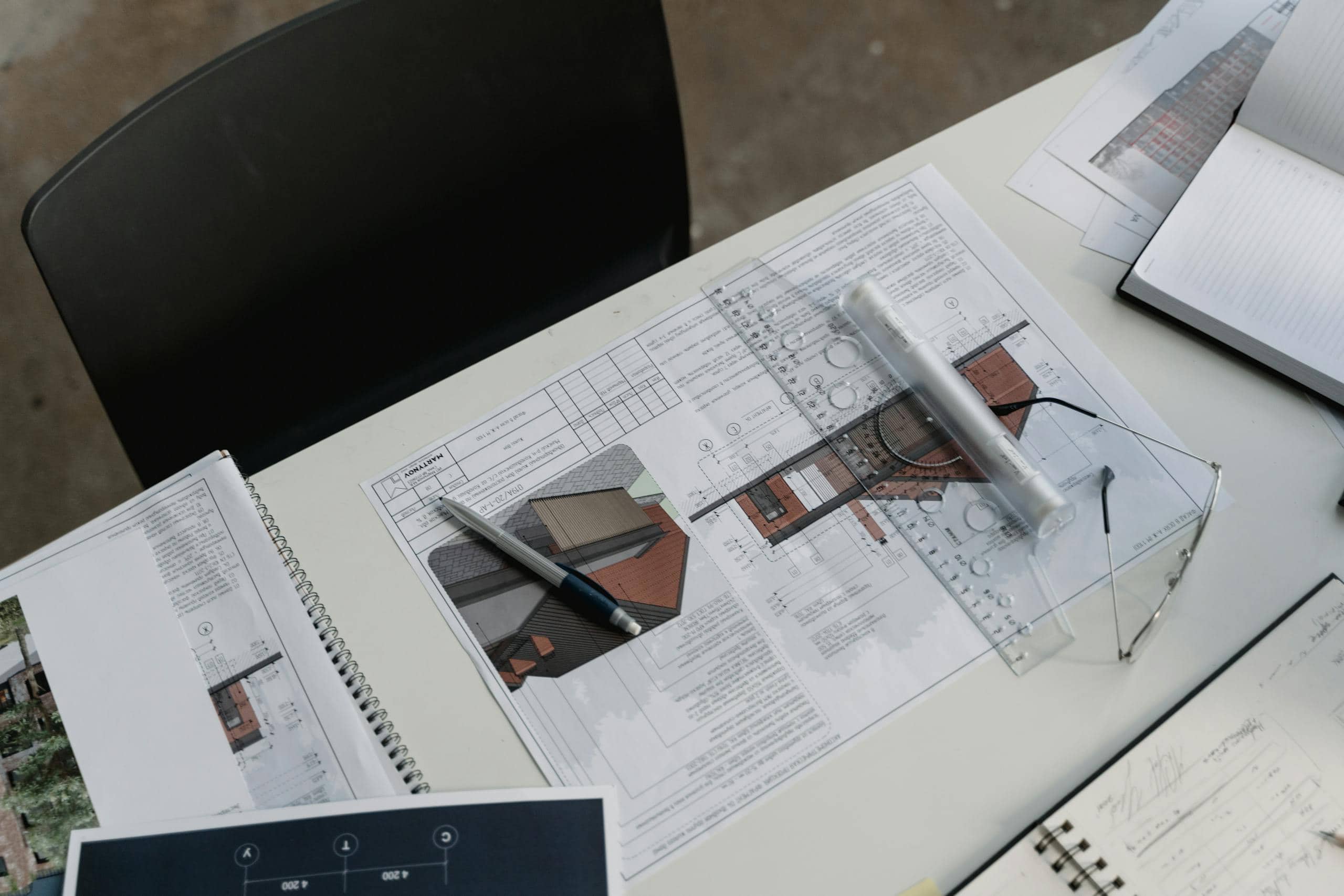 Top view of architectural blueprints and drafting tools on a workspace desk.